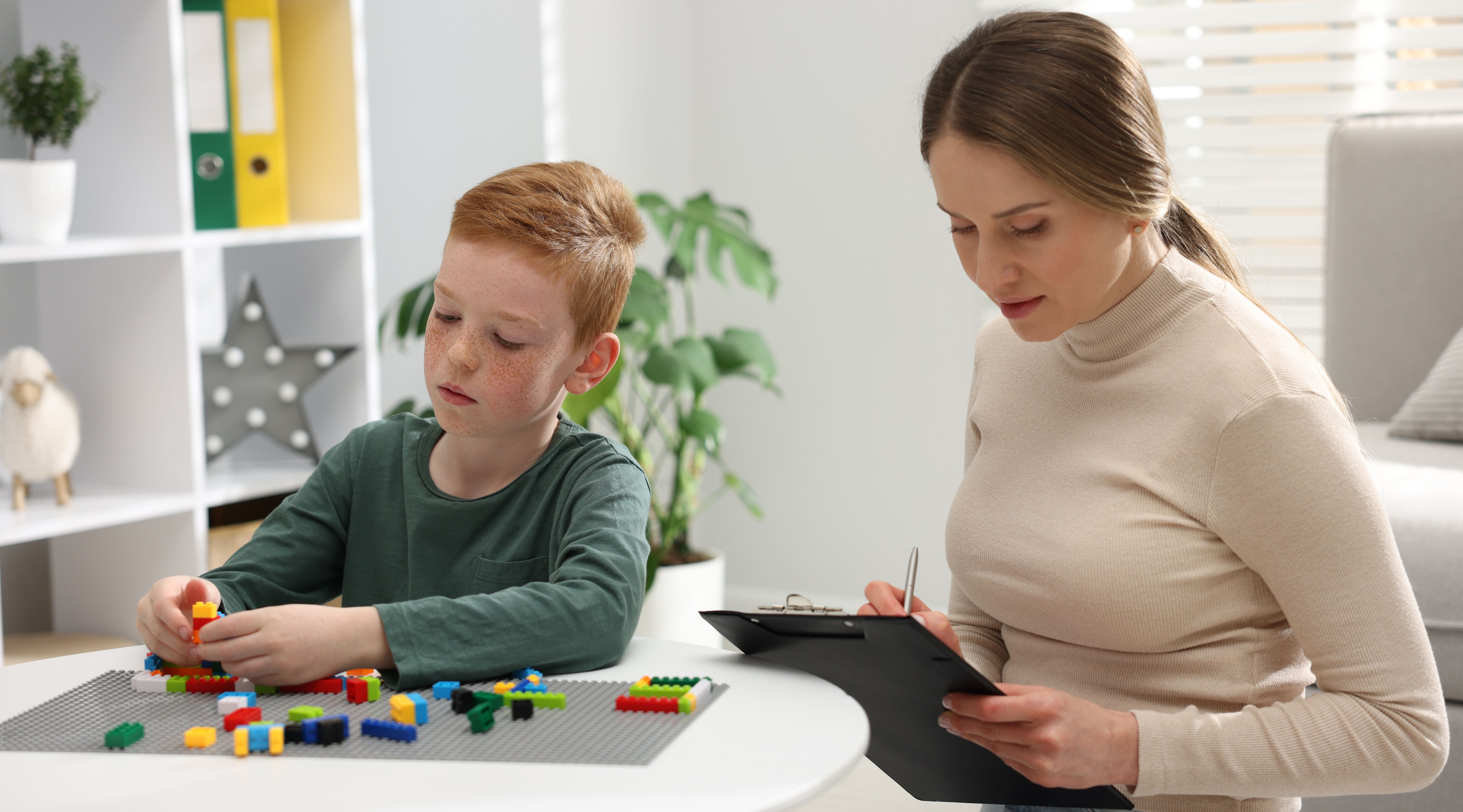 young boy who is playing with legos as a health provider is charting his behavior